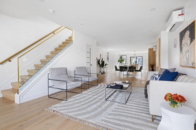 living area featuring baseboards, wood finished floors, stairway, and a wall mounted air conditioner