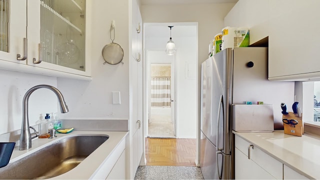 kitchen featuring a sink, light countertops, glass insert cabinets, white cabinets, and freestanding refrigerator