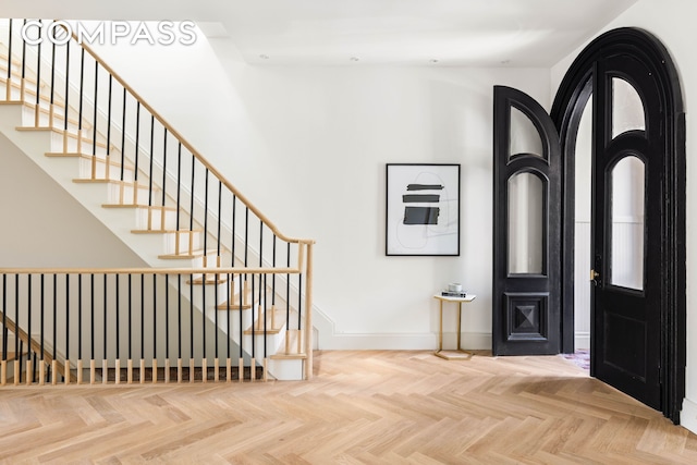 foyer featuring baseboards and stairway