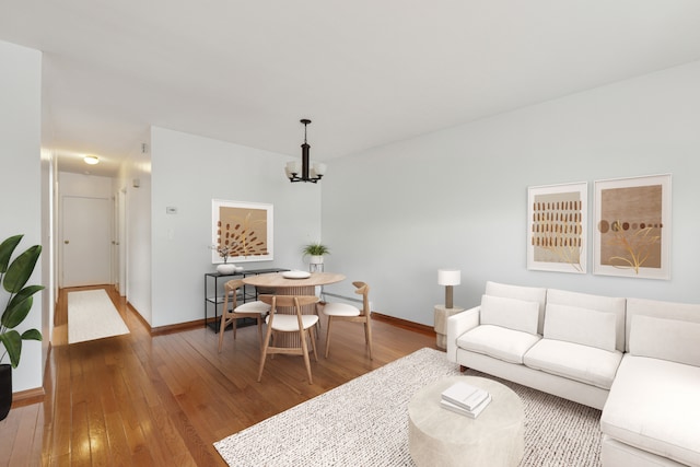 living room featuring wood-type flooring, baseboards, and a notable chandelier