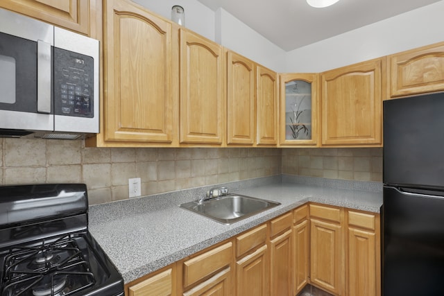 kitchen featuring glass insert cabinets, light countertops, a sink, backsplash, and black appliances