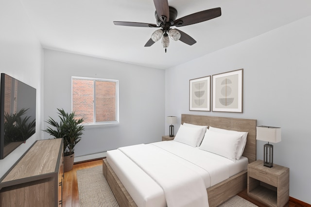 bedroom with baseboards, ceiling fan, baseboard heating, and wood finished floors