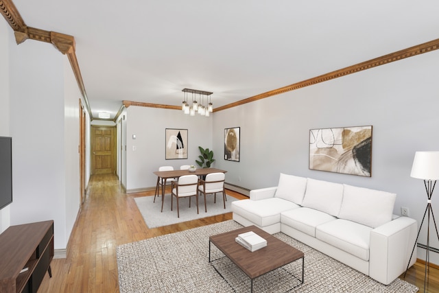 living room with crown molding, an inviting chandelier, light wood-style flooring, baseboards, and a baseboard heating unit