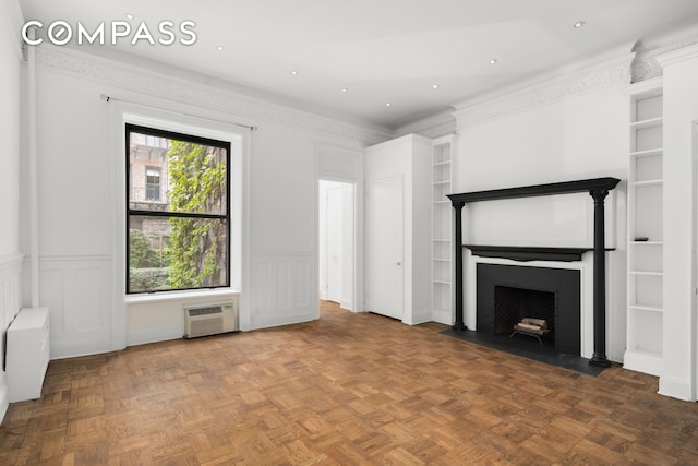 unfurnished living room featuring a fireplace with flush hearth, wainscoting, a decorative wall, and a wall unit AC