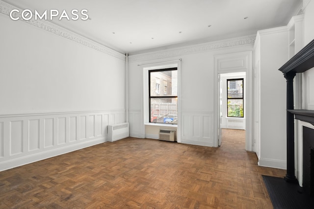 unfurnished living room with an AC wall unit, radiator, and wainscoting