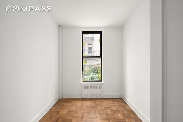 spare room with baseboards and radiator heating unit