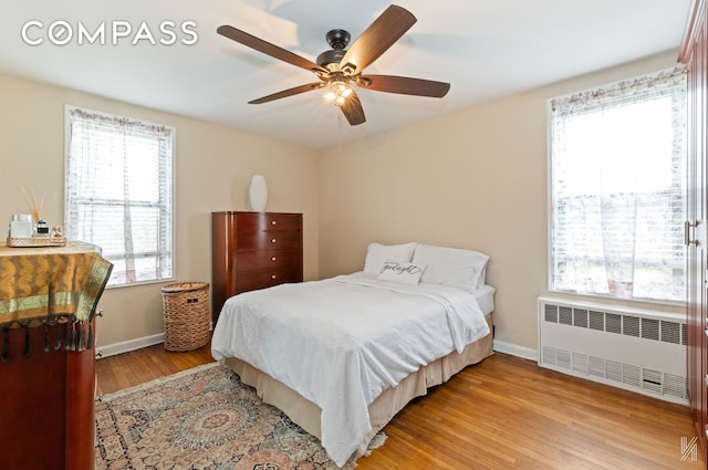 bedroom with baseboards, a ceiling fan, radiator, and light wood finished floors