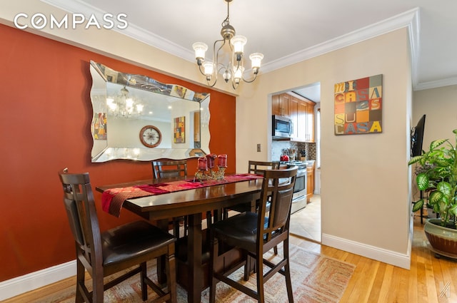 dining area featuring an inviting chandelier, baseboards, crown molding, and light wood finished floors