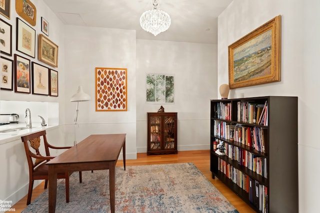 office featuring a sink, light wood-type flooring, a chandelier, and baseboards