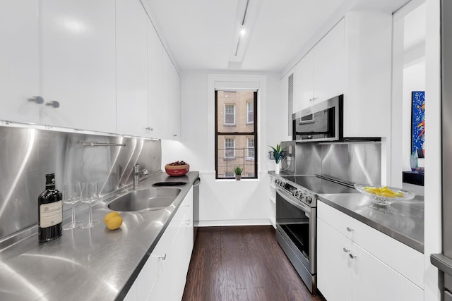 kitchen with dark wood-style flooring, stainless steel counters, white cabinetry, a sink, and stainless steel appliances