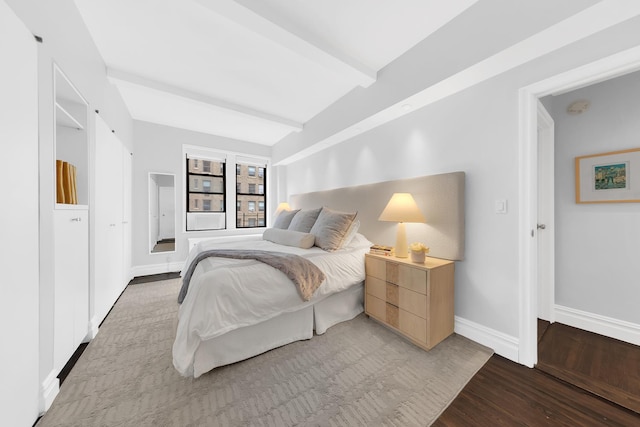 bedroom featuring baseboards, lofted ceiling with beams, and light wood-type flooring