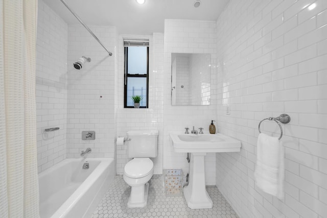 full bathroom with a sink, toilet, tile patterned floors, shower / bath combination with curtain, and tile walls