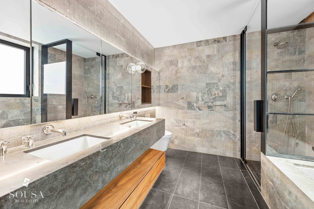 bathroom with tiled shower, toilet, tile walls, and a sink