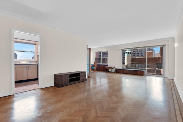 unfurnished living room featuring a sink, baseboards, and ornamental molding