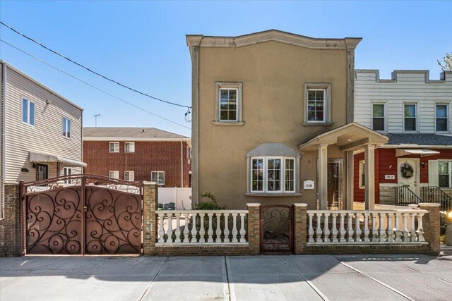 21-09 48th St, New York City, NY 11105 - townhome / multi-family property with stucco siding, a fenced front yard, and a gate