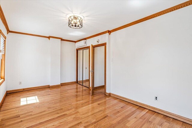 21-09 48th St, New York City, NY 11105 - empty room featuring a chandelier, light wood-style floors, ornamental molding, baseboards, and an AC wall unit