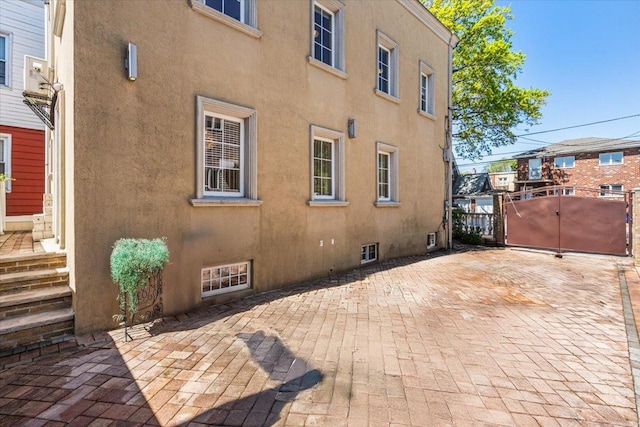 21-09 48th St, New York City, NY 11105 - view of property exterior with stucco siding, a gate, and a patio area