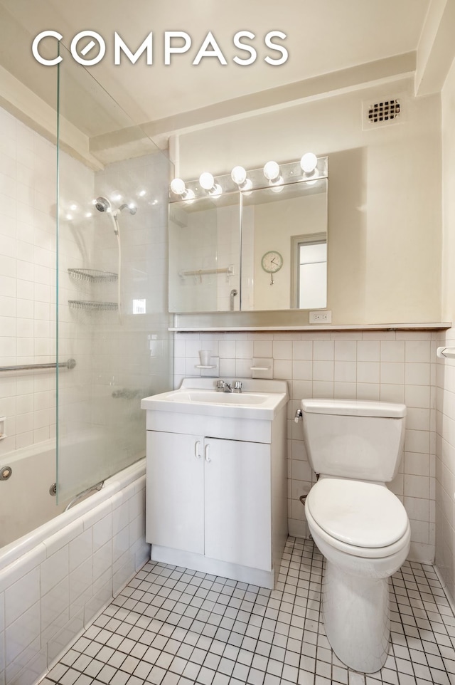 50 Park Ave Unit 15B, New York City, NY 10016 - bathroom featuring tiled shower / bath, tile patterned floors, toilet, tile walls, and vanity
