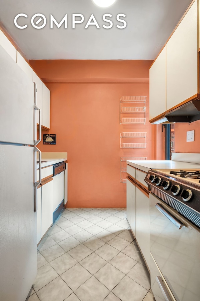 50 Park Ave Unit 15B, New York City, NY 10016 - kitchen with white appliances, white cabinets, light countertops, and light tile patterned flooring