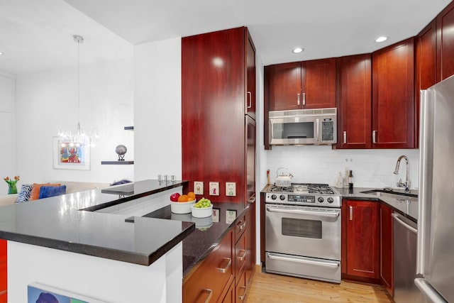 kitchen featuring reddish brown cabinets, a sink, light wood-style floors, and stainless steel appliances