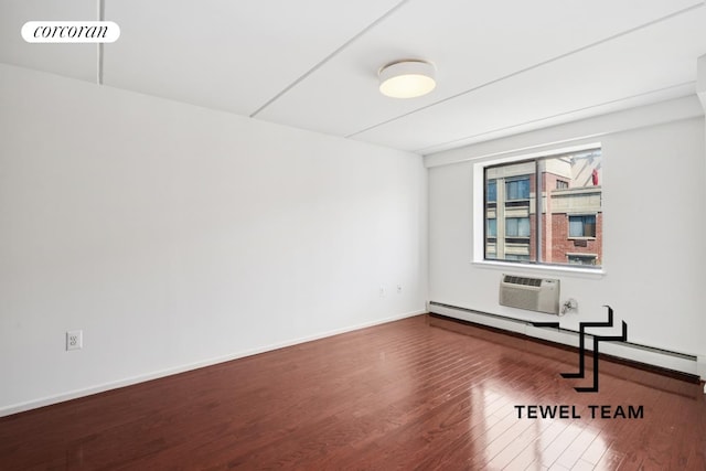 spare room featuring baseboard heating, baseboards, a wall unit AC, wood finished floors, and visible vents
