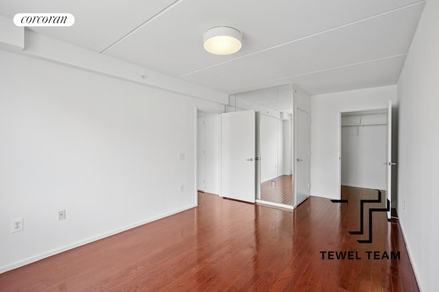 unfurnished bedroom featuring visible vents, baseboards, wood finished floors, and a closet