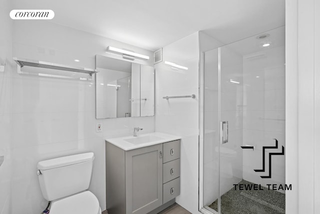 bathroom with vanity, a stall shower, toilet, and visible vents