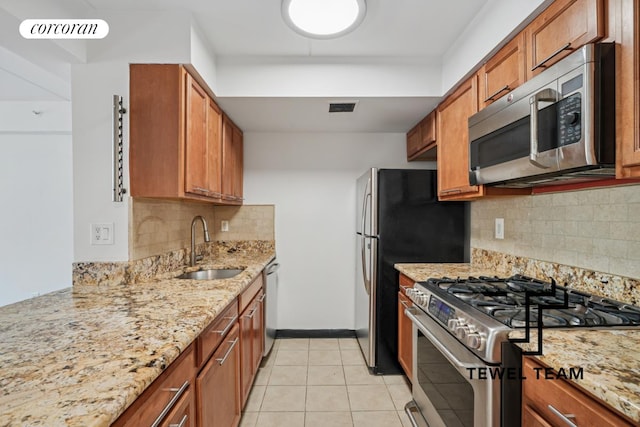 kitchen featuring stainless steel appliances, visible vents, a sink, and light stone counters