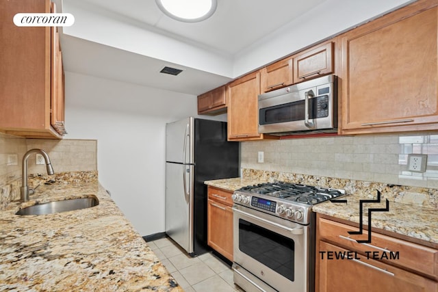 kitchen featuring a sink, appliances with stainless steel finishes, light tile patterned floors, and light stone counters