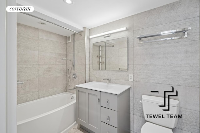bathroom with vanity, toilet, recessed lighting, tile walls, and bathing tub / shower combination