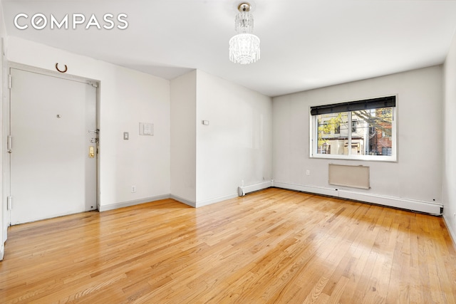 41-26 71st St Unit 1A, New York City, NY 11377 - unfurnished room featuring baseboard heating, light wood finished floors, a chandelier, and baseboards