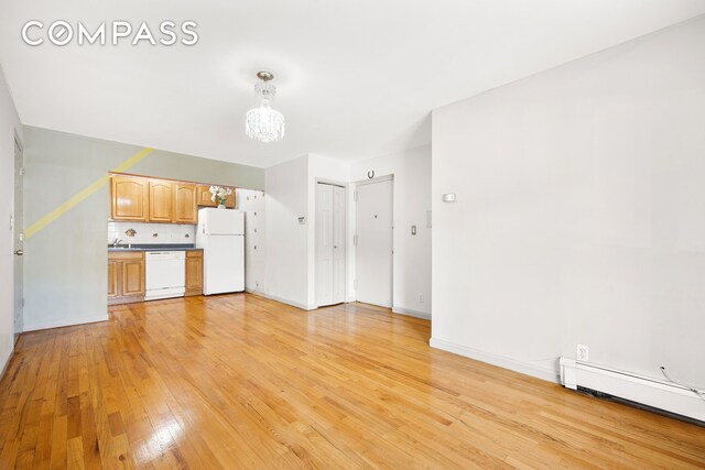 41-26 71st St Unit 1A, New York City, NY 11377 - unfurnished living room with light wood finished floors, a sink, baseboard heating, a chandelier, and baseboards