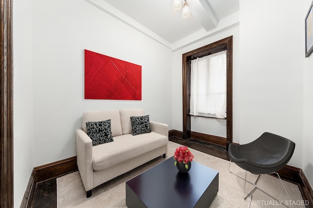living area featuring baseboards and beamed ceiling