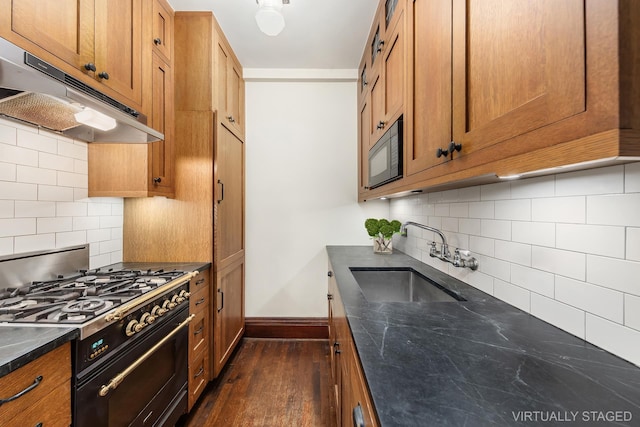 kitchen with black microwave, a sink, baseboards, under cabinet range hood, and range with gas cooktop