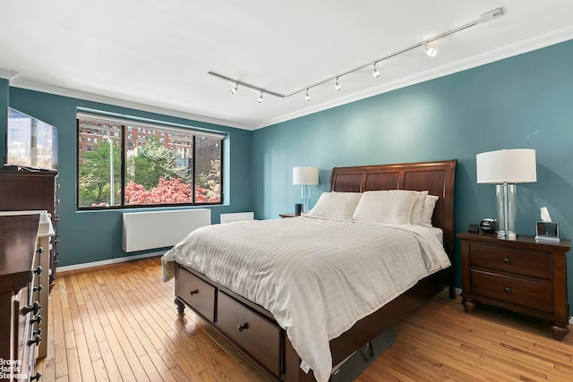 bedroom with crown molding, baseboards, track lighting, and radiator heating unit