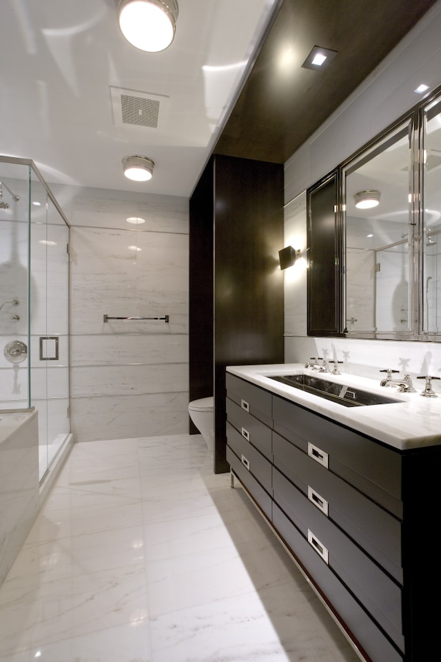 full bathroom featuring double vanity, toilet, tile walls, a shower stall, and visible vents