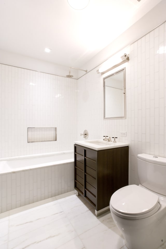 bathroom featuring vanity, marble finish floor, toilet, and tile walls