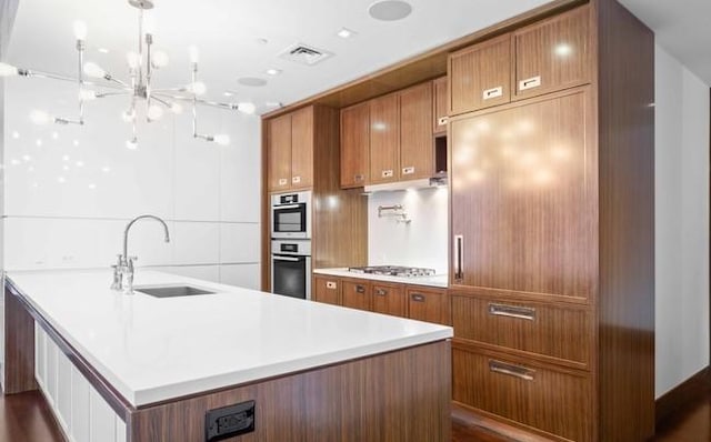 151 E 85th St Unit 12K, New York City, NY 10028 - kitchen with oven, brown cabinetry, gas stovetop, light countertops, and a chandelier