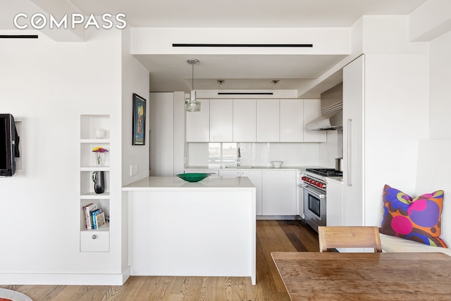 45 E End Ave Unit 6/7B, New York City, NY 10028 - kitchen with white cabinetry, dark wood finished floors, light countertops, wall oven, and pendant lighting