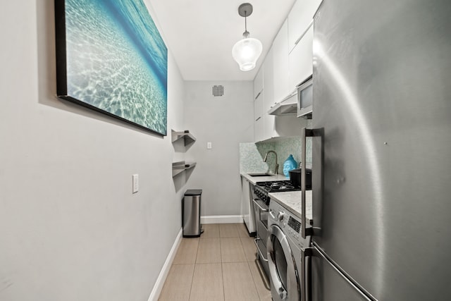 kitchen with white cabinets, appliances with stainless steel finishes, a sink, washer / clothes dryer, and visible vents