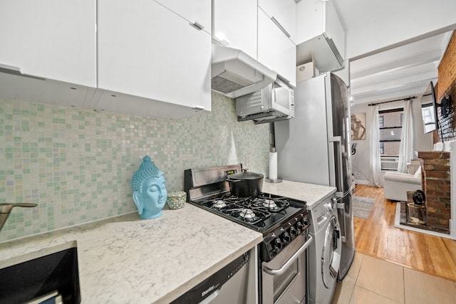 kitchen with washer / clothes dryer, white cabinetry, appliances with stainless steel finishes, and tasteful backsplash