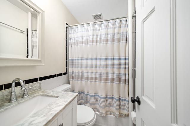 full bath featuring visible vents, tile walls, vanity, toilet, and shower / bath combo with shower curtain