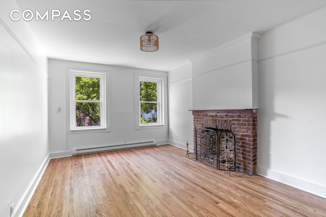 217 E 5th St Unit 6, New York City, NY 10003 - unfurnished living room with baseboard heating, wood finished floors, a fireplace, and baseboards