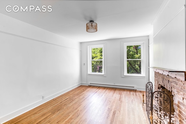 unfurnished living room with baseboards, a fireplace, a baseboard heating unit, and light wood-style flooring