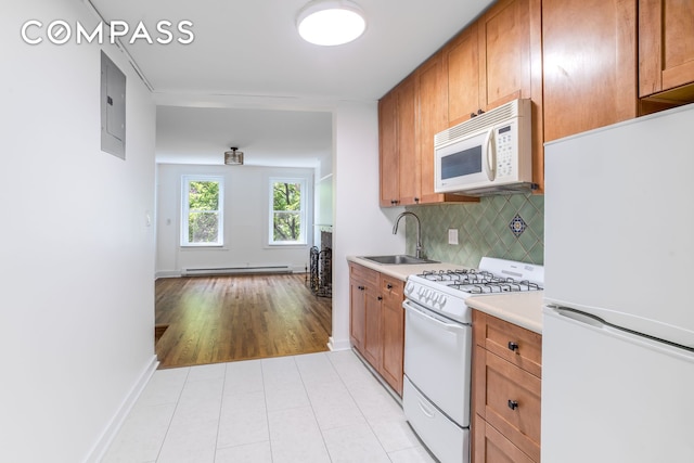 217 E 5th St Unit 6, New York City, NY 10003 - kitchen featuring white appliances, a sink, decorative backsplash, light countertops, and a baseboard radiator