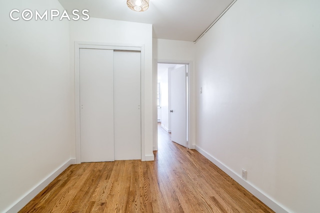 unfurnished bedroom featuring baseboards, a closet, and light wood-type flooring