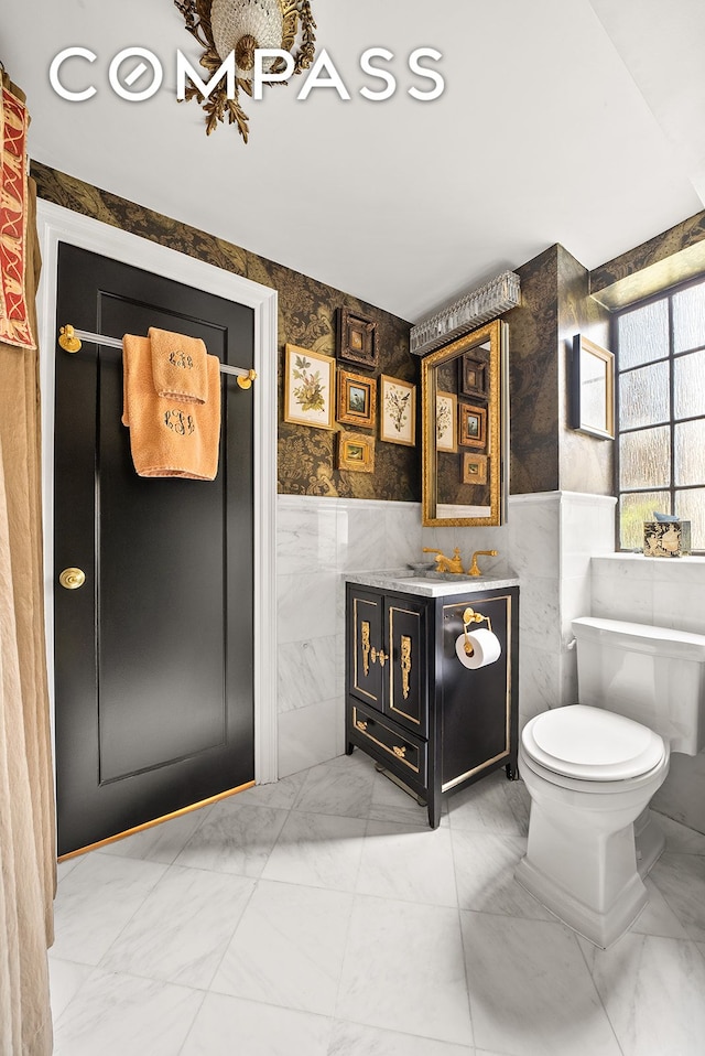 bathroom with toilet, tile walls, marble finish floor, and vanity