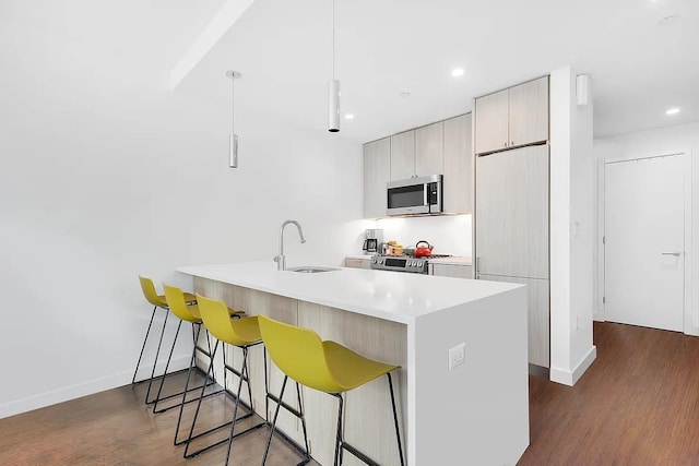 34-32 35th St Unit 3F, New York City, NY 11106 - kitchen featuring a breakfast bar area, stainless steel appliances, dark wood-style floors, and a sink