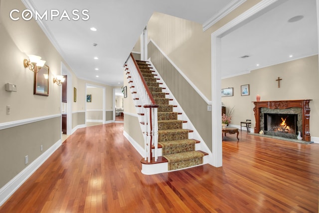 stairs with wood-type flooring, a high end fireplace, recessed lighting, and ornamental molding