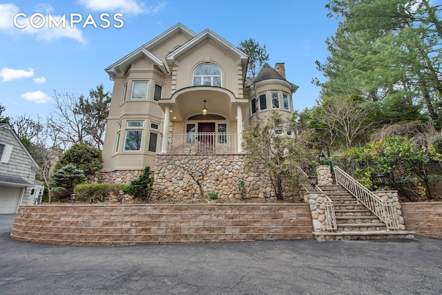 view of front of home with stucco siding, stone siding, and a chimney
